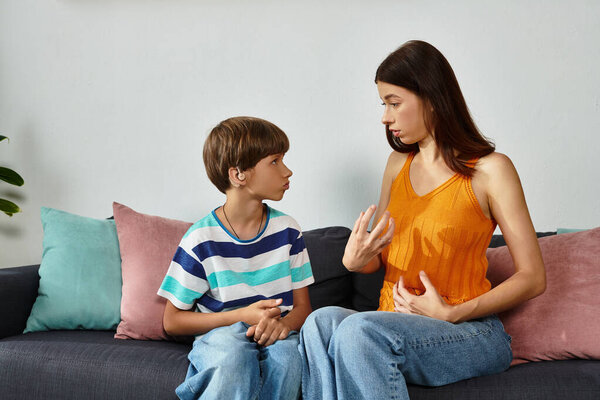 A mother lovingly interacts with her hearing impaired son in a comfortable setting at home.