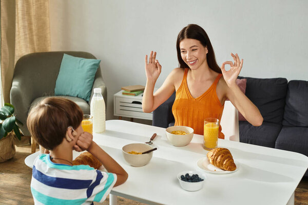 A caring mother shares a cheerful breakfast with her hearing impaired son, connecting through joy.