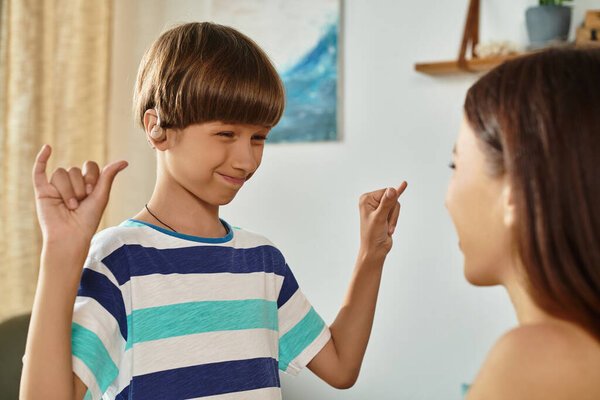 A mother and her son share a moment of joyful communication using sign language at home.