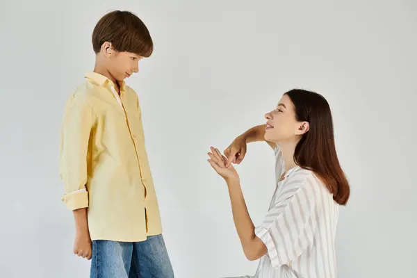 Stock image A mother engages creatively with her hearing impaired son, fostering connection and joy.