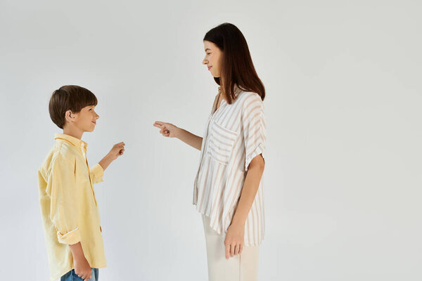 Мать взаимодействует со своим сыном, демонстрируя методы коммуникации для его нарушения слуха.