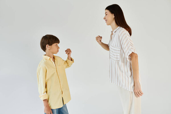 A young boy with hearing impairment learns sign language from his supportive mother in a studio.
