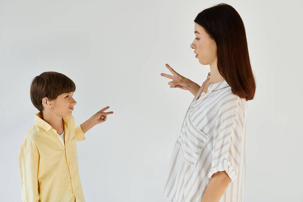 A mother and her son engage in a playful learning activity, signing and smiling together.