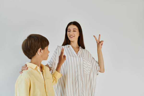 A mother playfully engages her hearing impaired son to promote learning.