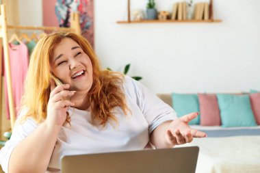 Neşeli bir kadın telefon konuşmasından zevk alıyor, rahat ve şık bir yaşam alanıyla çevrili..