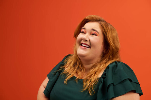 A joyful plus size woman smiles brightly, radiating confidence and warmth in a lively setting.