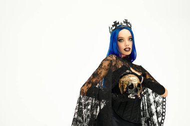 Genç bir kadın çarpıcı gotik Cadılar Bayramı kostümü, çarpıcı bir taç ve koyu renk makyajla modellik yapıyor..