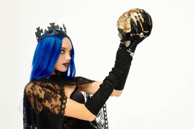 Bu büyüleyici genç kadın, dramatik bir şekilde kafatasını tutan gotik bir Cadılar Bayramı kostümü giyiyor..