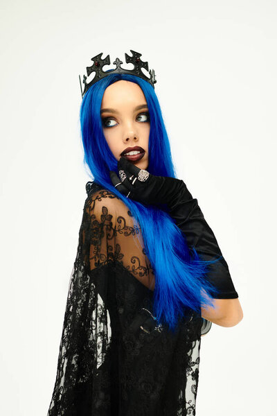 Красивая молодая женщина демонстрирует свой дух Хэллоуина с яркими голубыми волосами и одеждой.