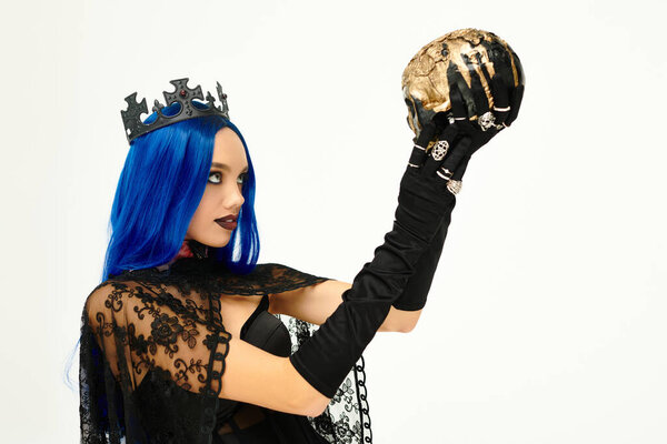 Эта очаровательная молодая женщина носит готический костюм на Хэллоуин, держа череп в драматической манере.