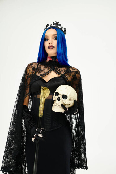 Молодая женщина в костюме призрака Хэллоуина элегантно позирует с черепом.