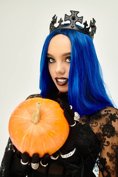 Молодая женщина в очаровательном костюме обнимает Хэллоуин, держа в руках тыкву.