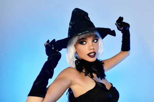 stock image A young woman showcases her striking Halloween witch costume with dramatic makeup and accessories.