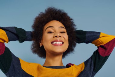 A young woman beams with joy, her hands behind her head, radiating positivity and confidence. clipart