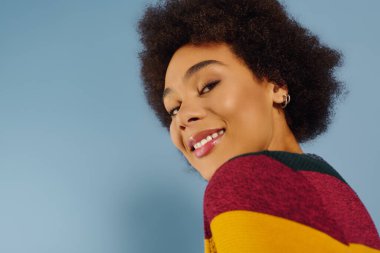 Neşeli genç bir kadın neşeli bir atmosferde canlı buklelerle parlar..