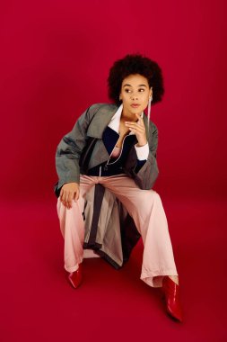 Çarpıcı kırmızı bir ortamda, genç bir kadın zarif bir şekilde poz verirken derin duygular ifade eder..