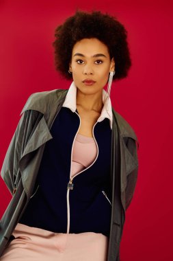 Genç bir kadın, parlak bir arkaplan önünde şık bir poz verirken duygularını açığa vurur..