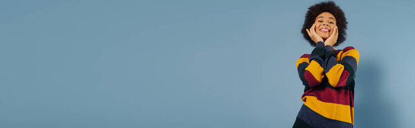 Молодая женщина излучает эмоции и счастье, игриво позируя с яркой улыбкой.