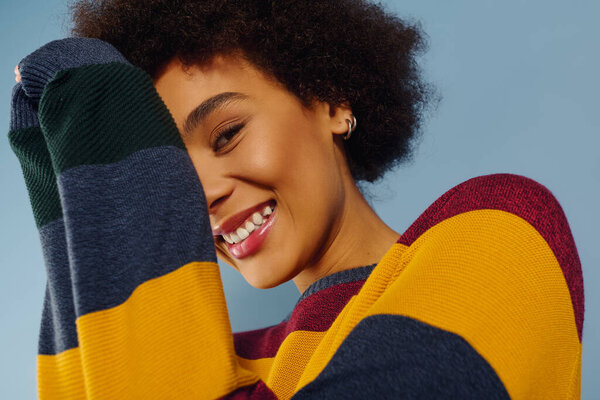 A joyful young woman embraces her vibrant personality with a bright smile and cozy sweater.