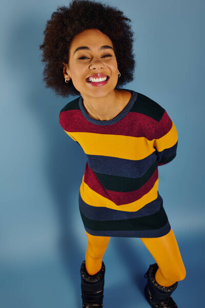 Веселая молодая женщина с заразительной улыбкой обнимает радость, позируя игриво.