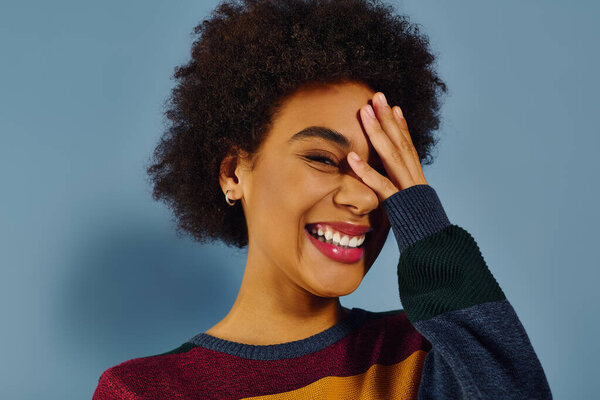 Молодая женщина с вьющимися волосами делится своим сердечным смехом, излучая позитив и радость..