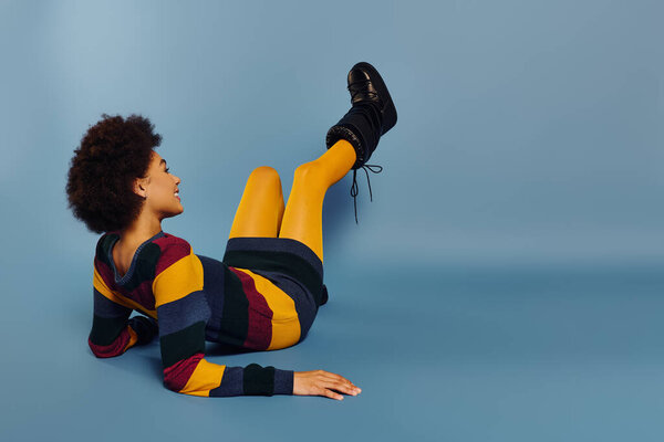 Живая молодая женщина в красочной одежде демонстрирует свои радостные эмоции, расслабляясь..