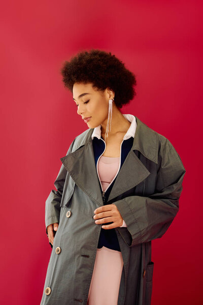 A young emotional woman reflects deeply while dressing in a fashionable coat.