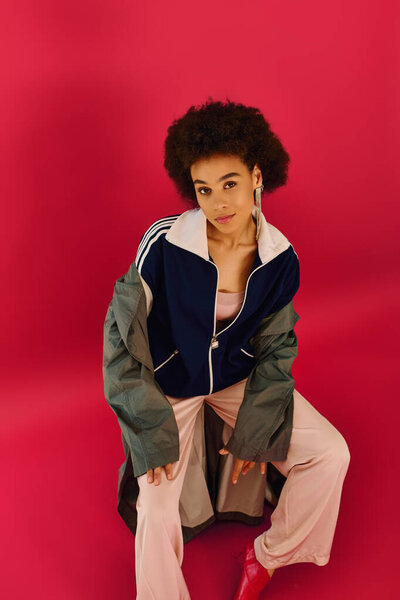 Эмоциональная молодая женщина в стильной одежде передает свои чувства в смелой обстановке.