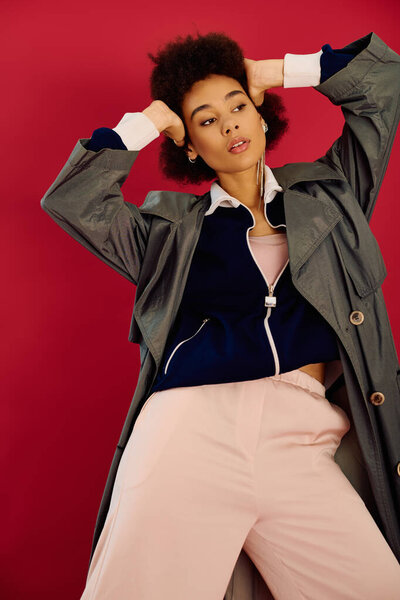 A young woman expresses deep emotions while posing in a fashion forward outfit against red.