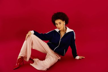 Genç bir kadın koyu kırmızı arka planda dinlenirken derin duygular ifade eder..