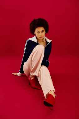 Kadın zarif bir şekilde oturuyor, duygularını cesur bir arka plana yansıtıyor..