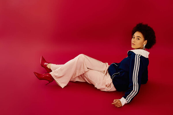 Молодая женщина с эмоциональным выражением лица модно позирует на полу в поразительной обстановке.