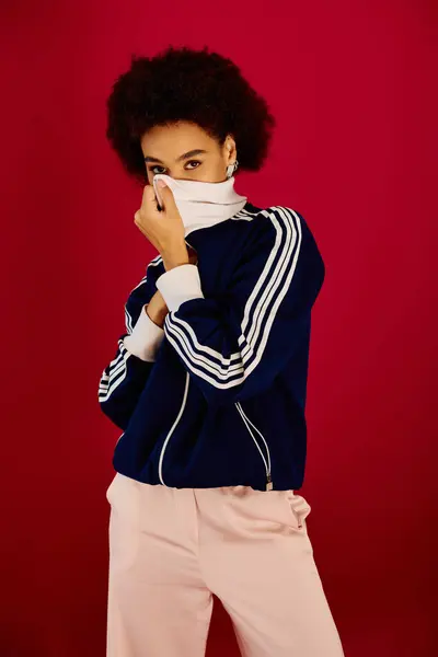 stock image A young woman reveals her emotions, playfully hiding her face in a vibrant studio backdrop.