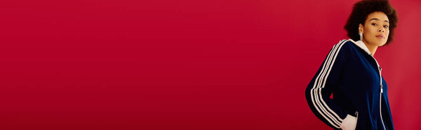 A young woman with expressive features stands against a vibrant red background, showcasing emotions.