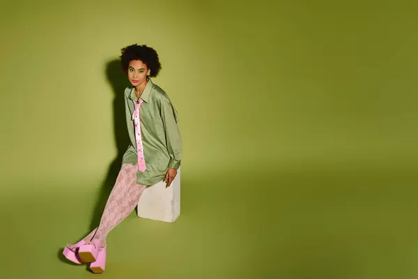 stock image A young woman in a vibrant outfit sits gracefully against a green background.