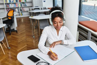 Profesyonel bir öğretmen, bir defter ve kulaklıkla ilgi kurma dersleri hazırlar..