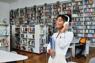 A devoted African American teacher enjoys music and books while prepping for class. clipart