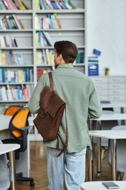 A handsome student strides purposefully through a library, eager to engage with his studies. clipart