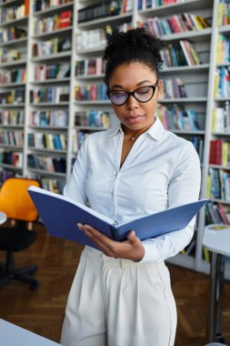 Canlı bir kütüphanede kitap okuyan tutkulu bir eğitimci..