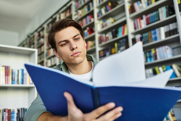 Самоотверженный студент сосредоточен на своей учебе в хорошо заполненной библиотеке.