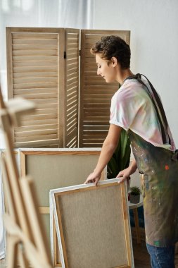 A young woman in casual attire gets ready to create a beautiful painting in her inviting home space. clipart