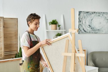 Genç bir kadın sanatsal yeteneğini ve neşesini ifade ederek huzurlu bir stüdyoda tuvaliyle meşgul oluyor..