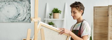 A young woman with natural makeup engages in painting, immersed in her creative process at home. clipart