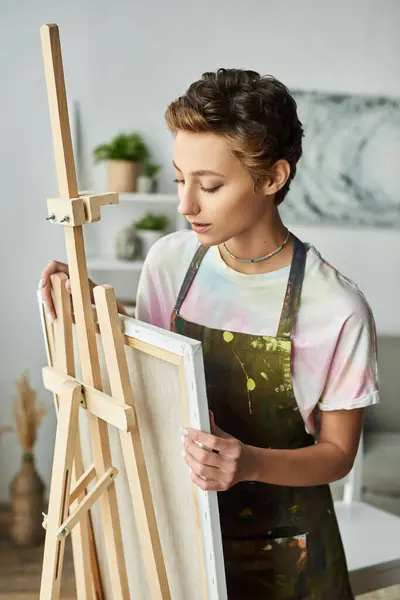 stock image In a cozy home setting, a young woman with short hair focuses intently on her new painting.