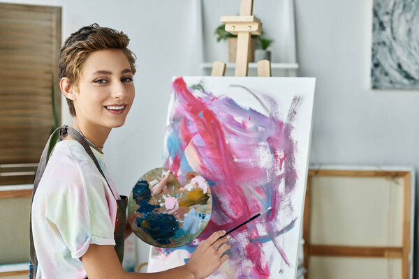 A young woman joyfully paints a colorful artwork at home, showcasing her passion for art and creativity.
