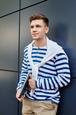 Protez bacaklı genç bir adam gururla duvarın önünde duruyor ve tarzını gösteriyor..