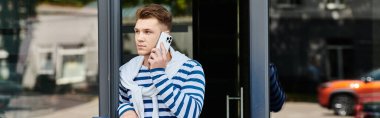 Protez bacaklı kendine güvenen genç bir adam telefonuyla konuşuyor, dışarıda aydınlık bir günü kucaklıyor..