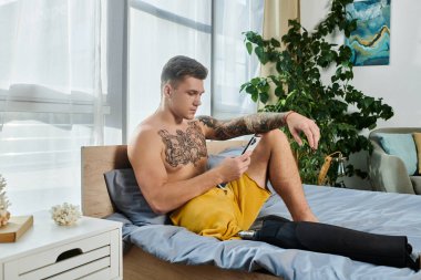 Sıcak bir odada, protez bacaklı genç bir adam yatağında dinlenmenin keyfini çıkarıyor..