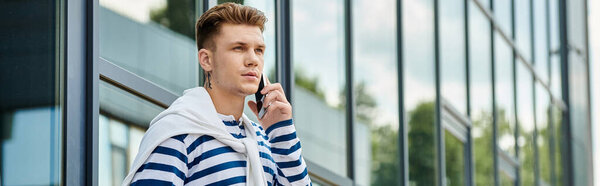 Молодой человек с протезной ногой задумчиво стоит возле гладких стеклянных зданий..