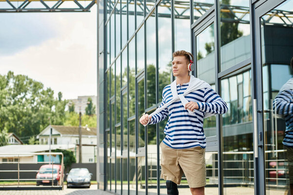 This young man, wearing a striped shirt, steps forward with confidence in a lively urban setting.
